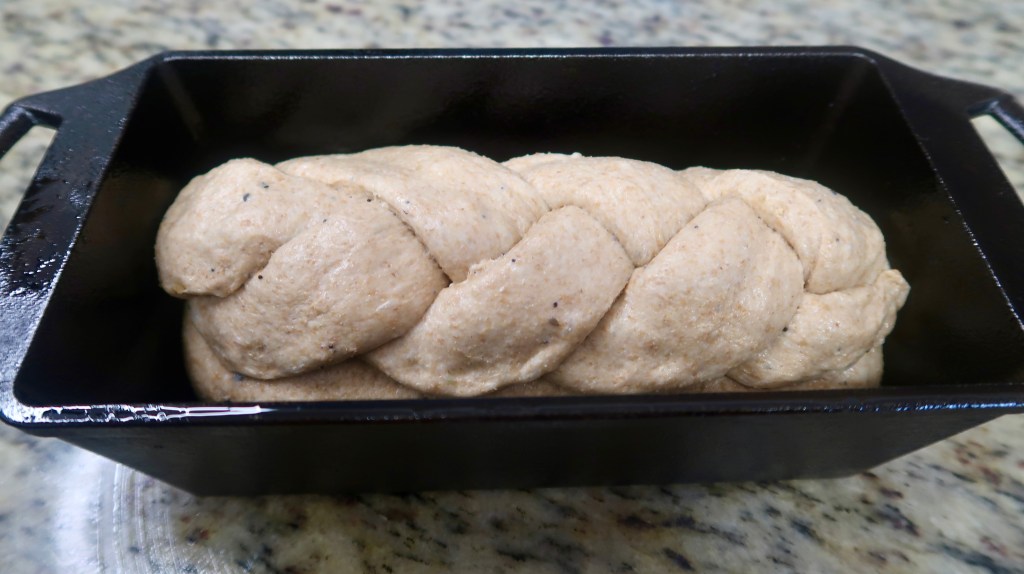 Braided dough placed in a rectangular cast iron baking pan.