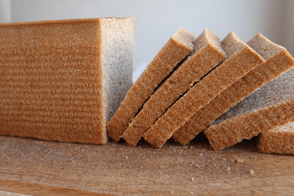 Sliced whole grain bread laid on a wooden cutting board.