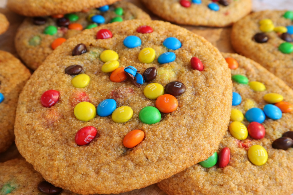 Close-up of golden brown cookies topped with colorful candy-coated chocolate pieces.