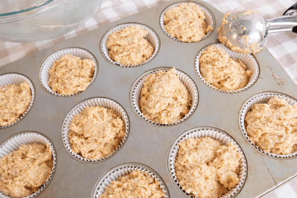 Muffin batter portioned into lined cupcake trays ready for baking.