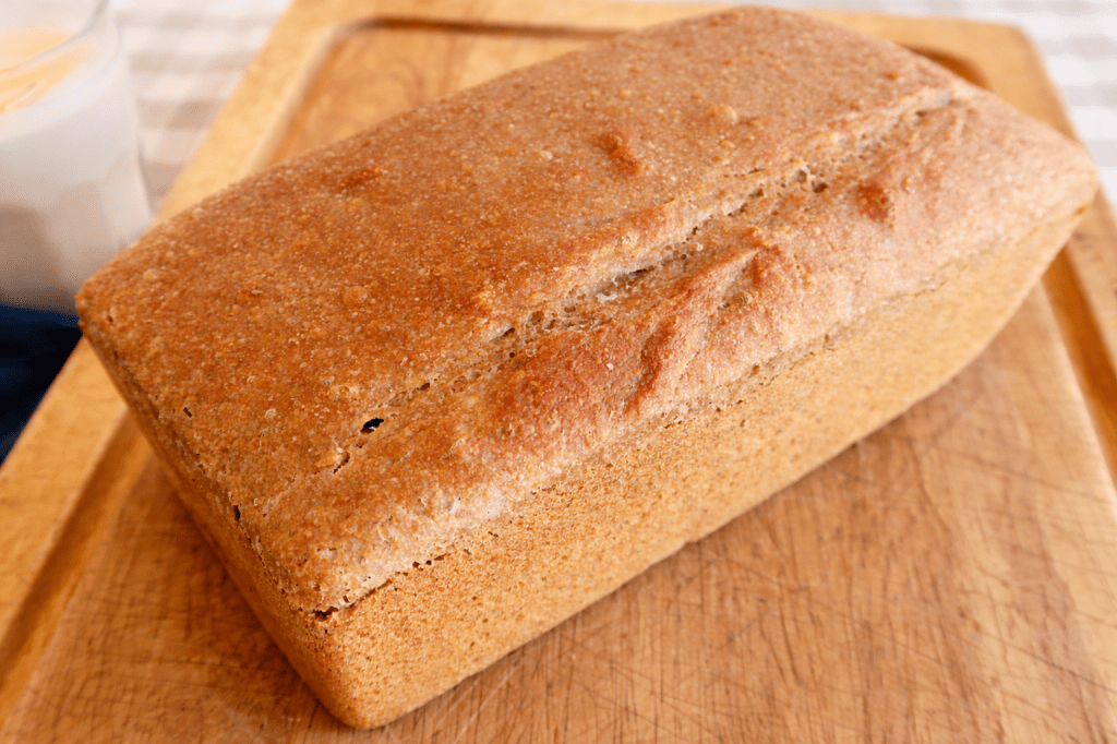 Freshly baked whole grain bread on a wooden cutting board.