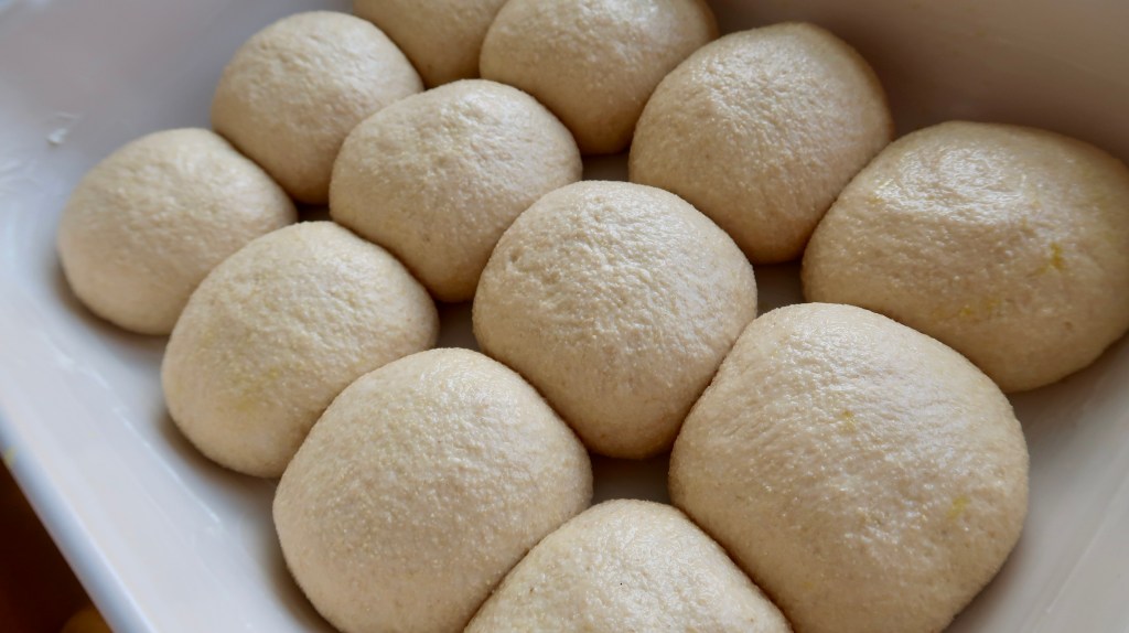 A close-up view of soft, round dough balls resting in a dish, ready for baking.