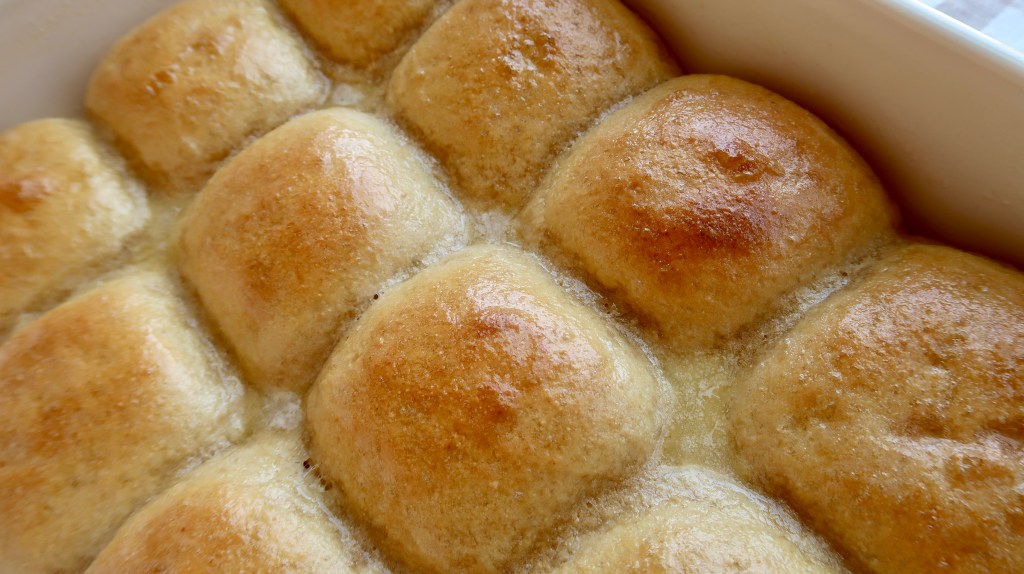 Golden brown, freshly baked dinner rolls arranged in a baking dish.