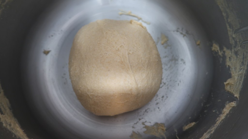 A smooth, golden ball of dough resting inside a mixing bowl.